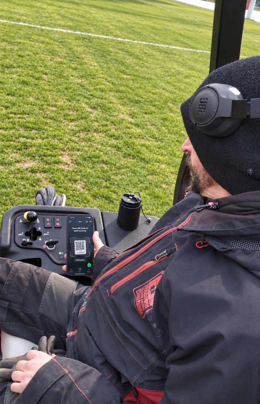 A groundskeeper scanning a mower’s QR code with the turfcoach app before starting work